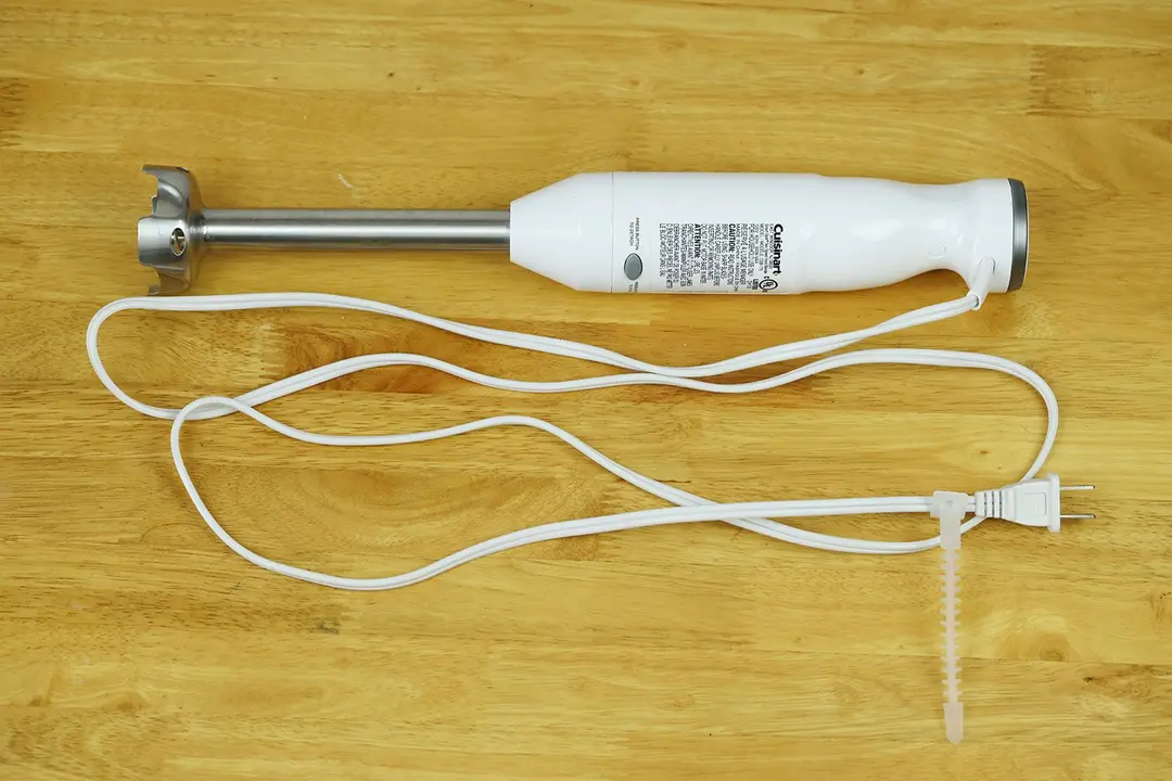 The Cuisinart Smart Stick Immersion Blender on a gray table with its power cord rolled up next to it.