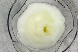 Looking down at stiff peak egg whites in the 24-oz plastic beaker from above.