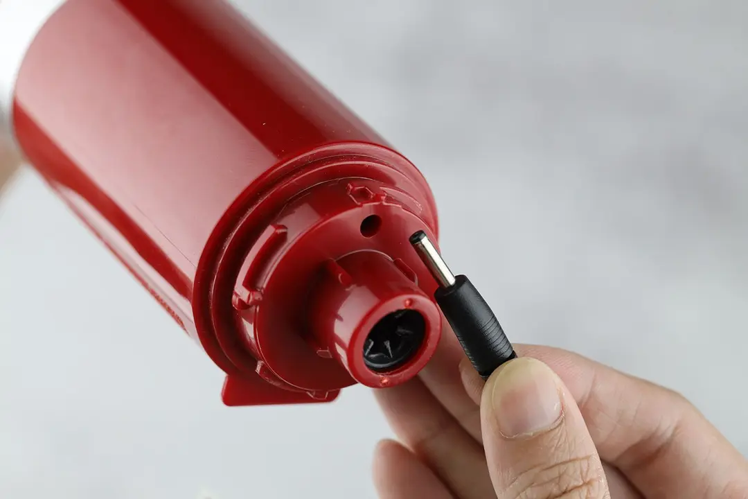 A close-up of the charging port and charger adapter pin of the KitchenAid stick blender.