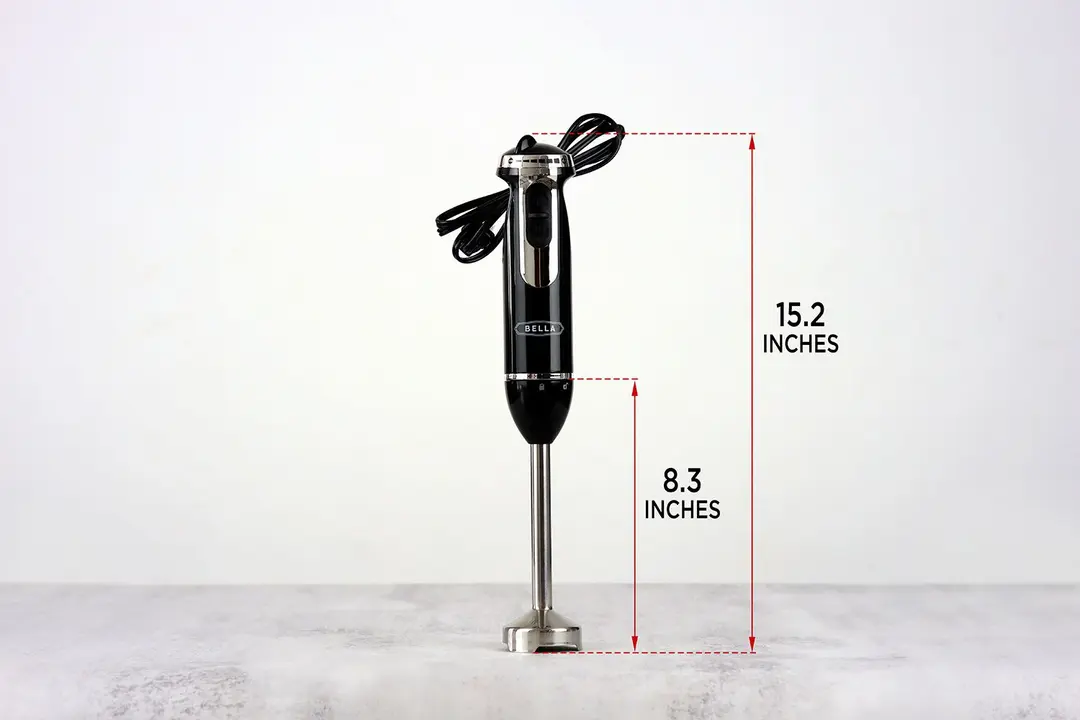The BELLA Immersion Blender standing on top of its blending shaft on a gray table, with the length of the blending shaft being noted to the side as 8.3 inches, and the total length of the unit as 15.2 inches. 