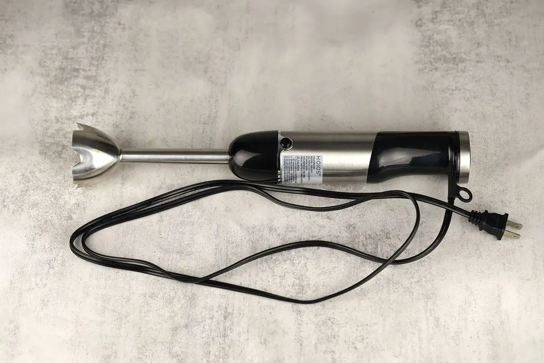The KOIOS 4-in-1 Immersion Blender on a gray table with its power cord rolled up next to it.