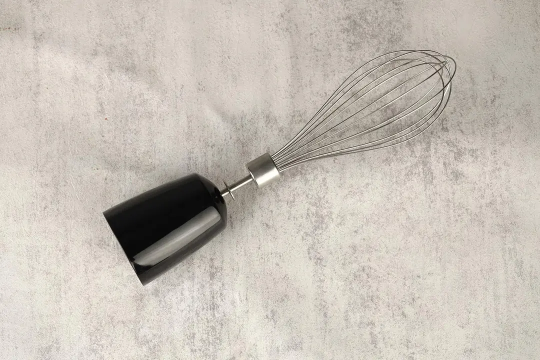 The KOIOS 4-in-1 Immersion Blender Whisk Attachment lying flat on a gray table.