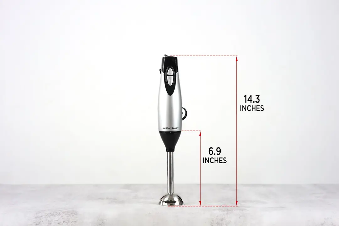 The Hamilton Beach Immersion Blender stands on top of its blending shaft on a gray table, with the length of the blending shaft being noted to the side as 6.9 inches, and the total length of the unit as 14.3 inches.