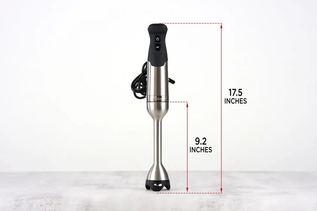 The Vitamix stainless steel immersion blender stands on top of its blending shaft on a gray table, with the length of the blending shaft being noted to the side as 9.2 inches, and the total length of the unit as 17.5 inches.