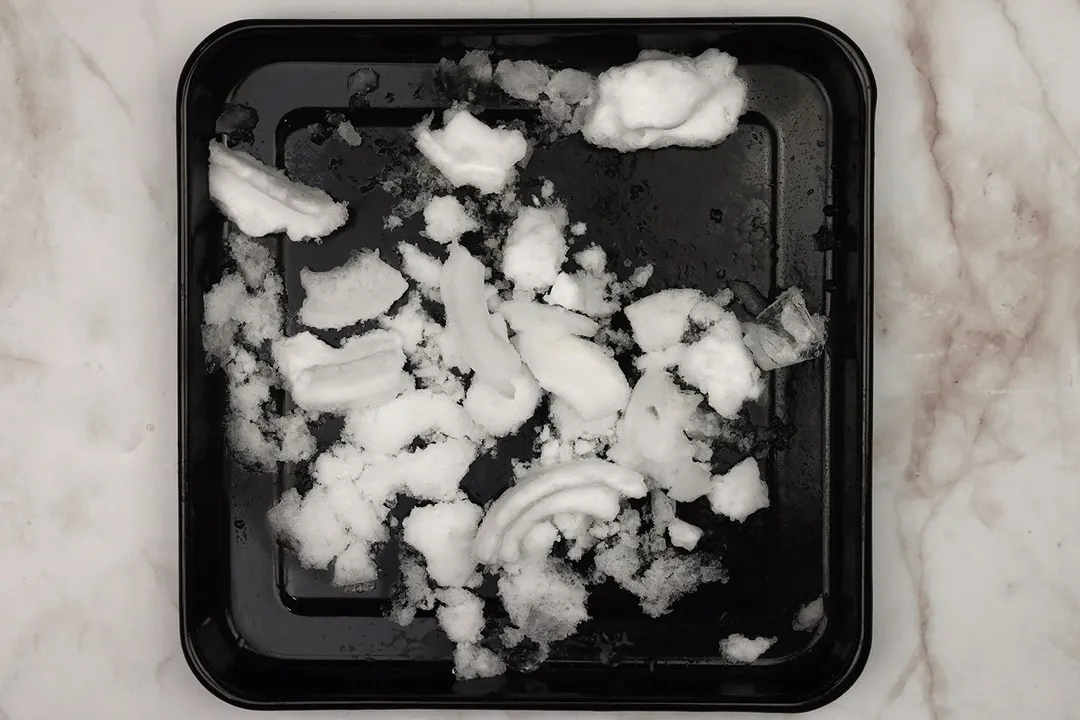 A black tray of fine crushed ice on a table. 