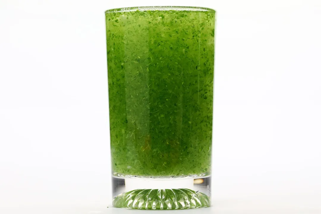 A glass of water with fibrous green pulp produced by the Magic Bullet personal blender.