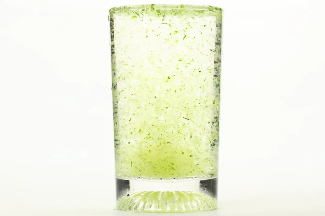 A glass of water with fibrous green pulp produced by the NutriBullet single-serve blender.