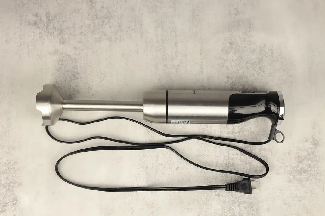 The Mueller Ultra-Stick Immersion Blender on a gray table with its power cord rolled up next to it.