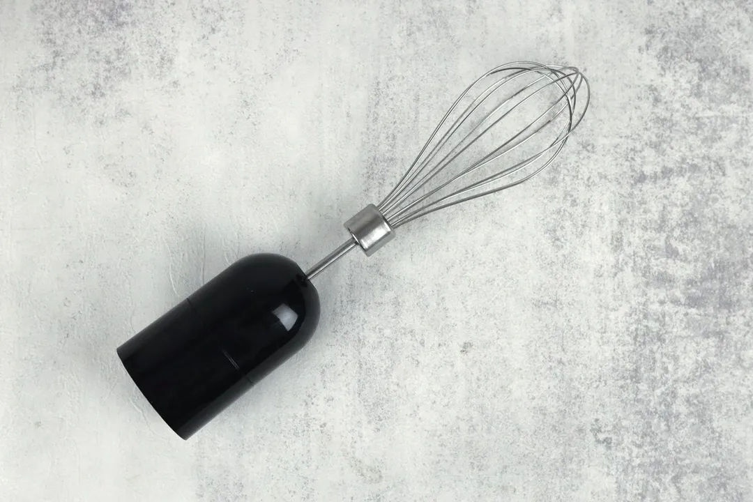 The Mueller Ultra-Stick Immersion Blender Whisk Attachment lying flat on a gray table.