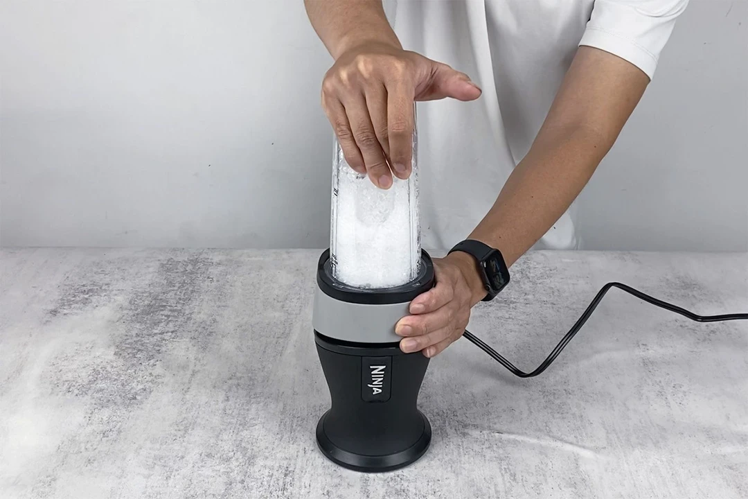 Someone is performing the ice-crushing test on the Ninja Fit personal blender. 