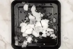 A black tray of crushed ice produced by the Ninja Fit Personal Blender being on a table.