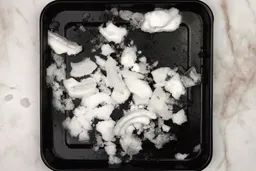 A black tray of crushed ice produced by the Nutribullet Pro 900-watt Personal Blender being on a table. 