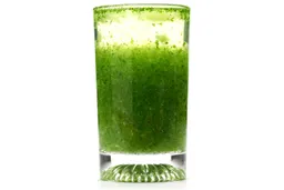 A glass of water with fibrous green pulp produced by the Nutribullet Pro 900-watt Personal Blender sinking from its top to bottom.