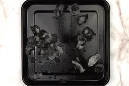 A black tray of crushed ice produced by the Magic Bullet Single-Serve Blender being on a table.