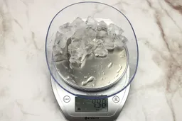 The amount of unblended ice cubes (4.98 oz) of the Magic Bullet single-serve blender displayed on a scale’s screen.
