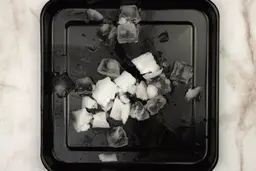 A black tray of crushed ice produced by the KOIOS Personal Blender being on a table.