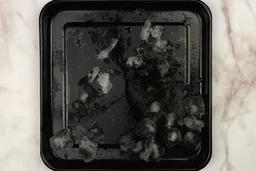A black tray of crushed ice produced by the Hamilton Beach Blender being on a table. 
