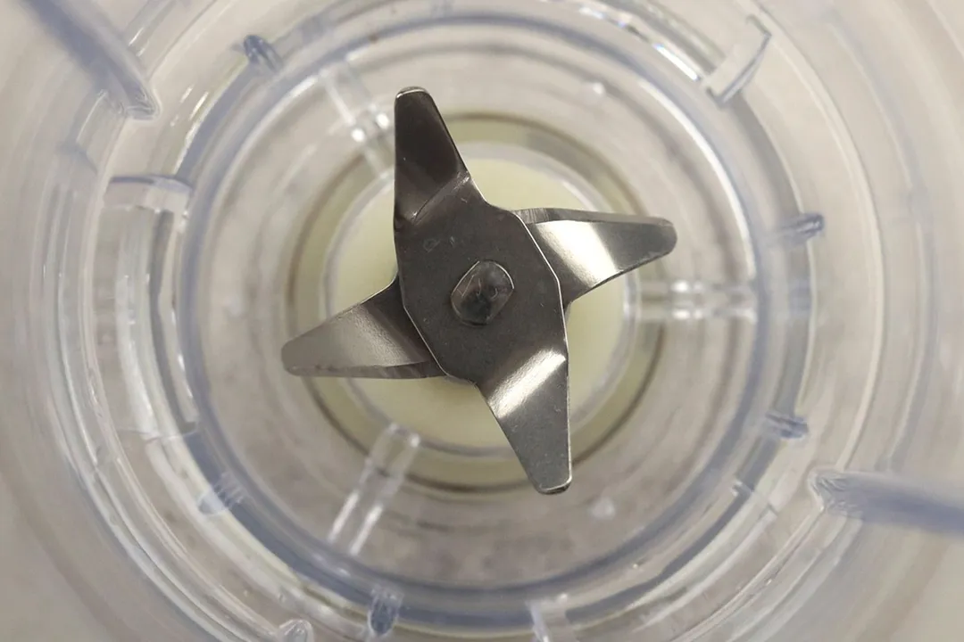 A close-up of the blade assembly featuring 4 stainless steel prongs inside the blending cup of the Hamilton Beach personal blender. 