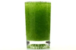 A glass of water with fibrous greens pulp produced by the Black+Decker Fusionblade Single-Serve Blender.