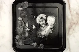 A black tray of crushed ice produced by the Oster Smoothie Maker Blender being on a table.