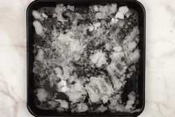 A black tray of crushed ice produced by the Nutri Ninja Personal Blender being on a table. 