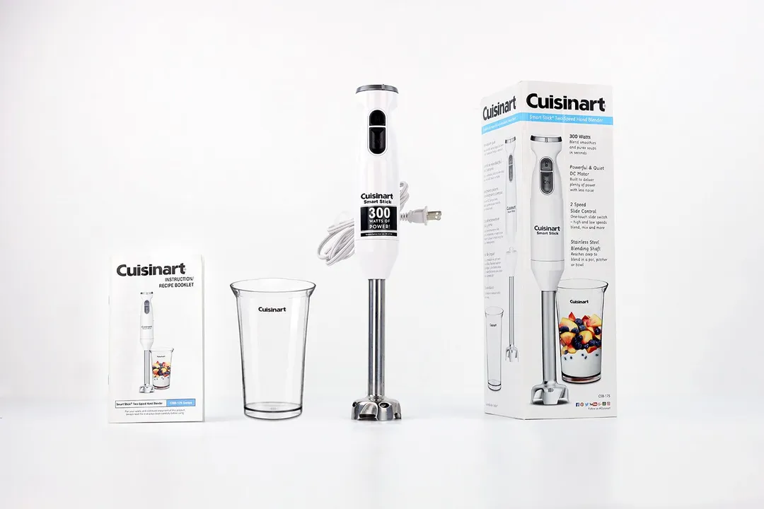 Unboxing the Cuisinart Smart Stick Hand Blender; from left to right: an owner's manual, paper carton box, blending wand with a motor body attached, and a plastic beaker. 