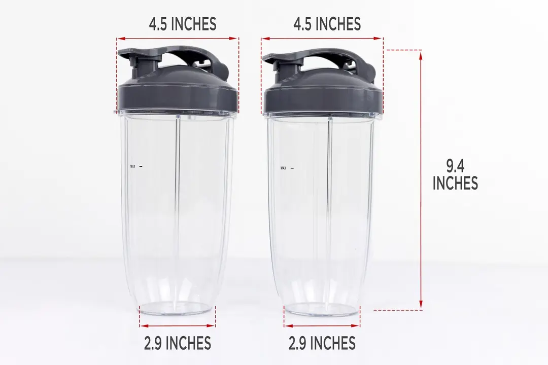 Two blending cup of the NutriBullet Pro 900-watt personal blender standing on a gray table, with the width of their top and bottom being noted to the side as 4.5 inches and 2.9, respectively, and the total length of the unit as 9.4 inches.