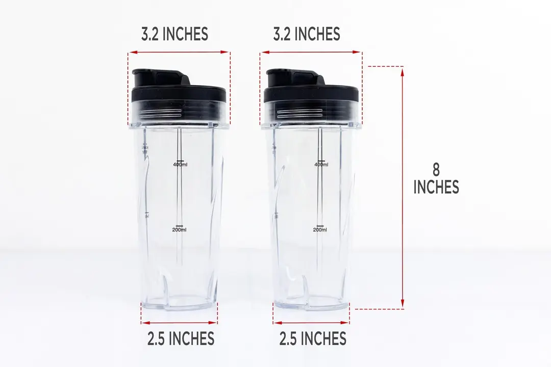 Two blending cups with lids of the Ninja Fit personal blender stand on a gray table, with the width of their top and bottom being noted to the side as 3.2 inches and 3.5, respectively, and the total length of the unit as 8 inches.
