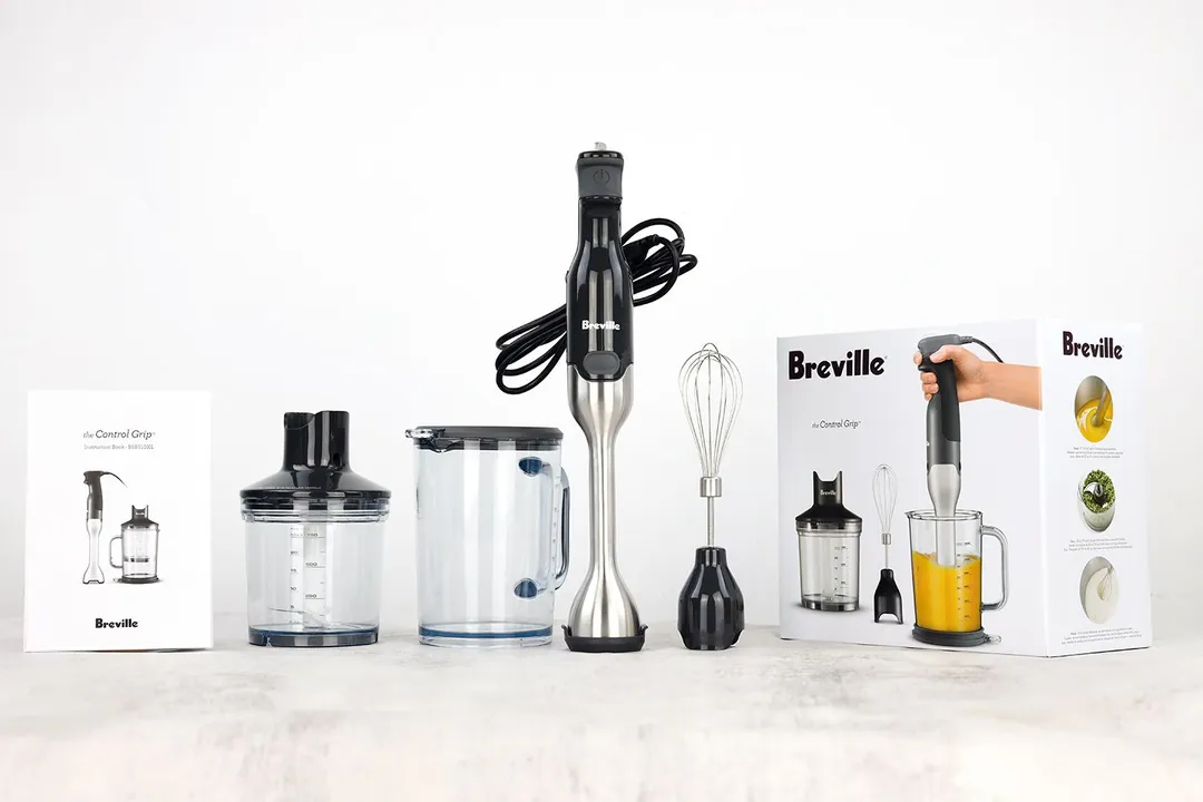 The Breville BSB510XL Immersion Blender is packed in a paper carton box with a motor body, blending shaft, wish attachment, food processor attachment, plastic beaker with lid, and a user’s manual.