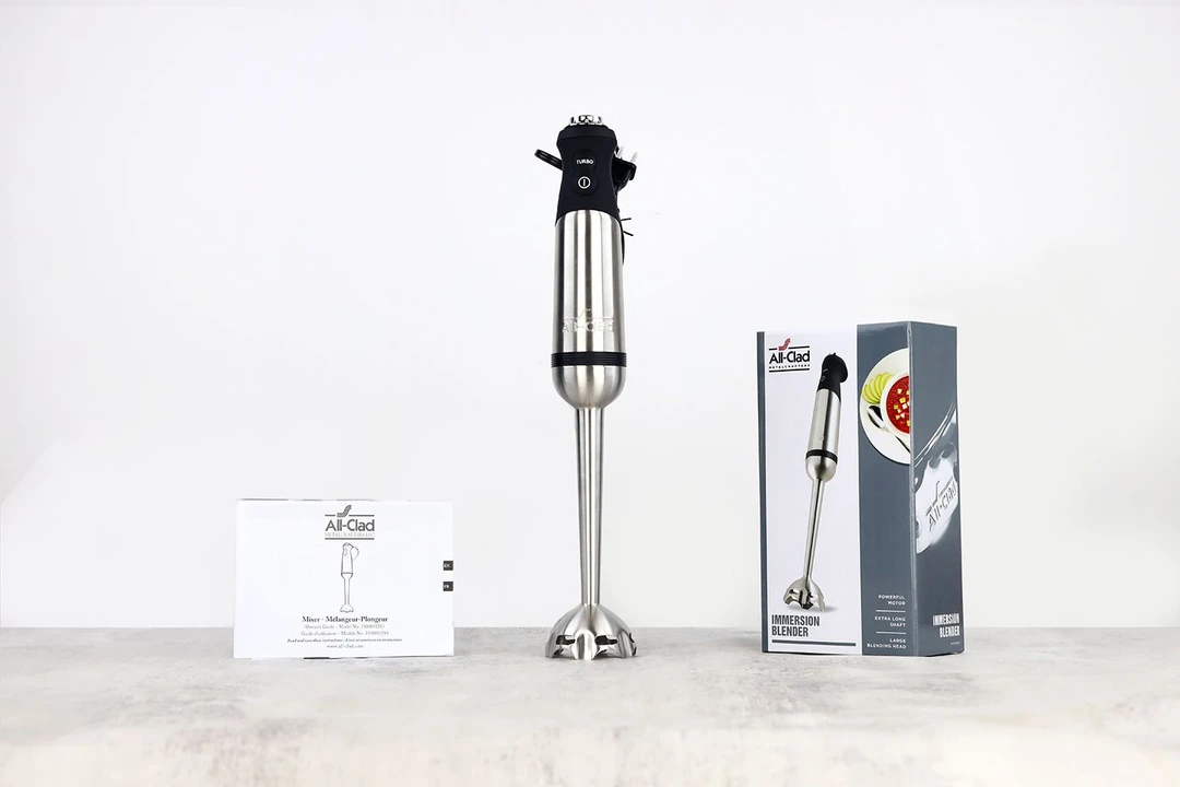 Unboxing the All-Clad Hand Blender, from left to right: a user’s manual, the All-Clad immersion blending wand with its motor body attached, and a paper carton box.