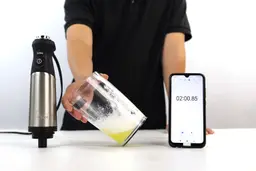 All-Clad immersion blender review: a paper carton box, the All-Clad blending wand with its motor body attached, and a user’s manual lying side by side on a white table.