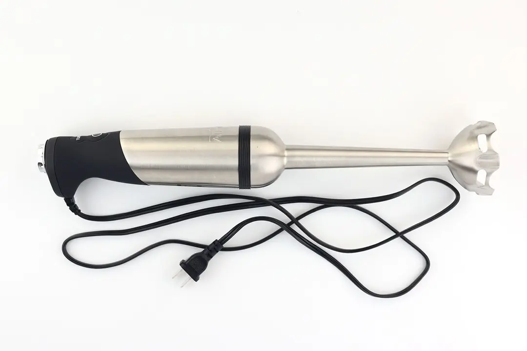 The All-Clad Immersion Blender on a white table with its power cord that features a 2-prong plug rolled up next to it.
