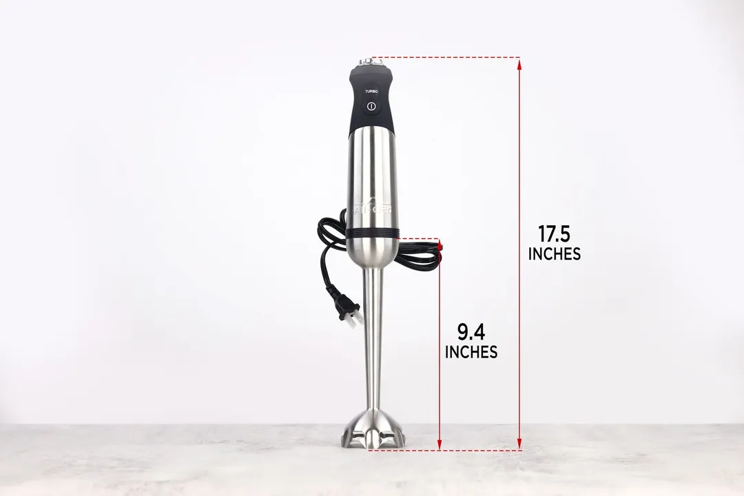 The All-Clad immersion blender standing on top of its blending shaft on a gray table, with the length of the blending shaft being noted to the side as 9.4 inches, and the total length of the unit as 17.5 inches.