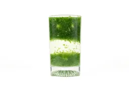A glass of water with fibrous green pulp produced by the iCucina Personal Blender sinking from its top to bottom.