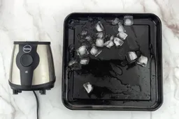 A black tray of crushed ice produced by the iCucina Single-Serve Blender being on a table.