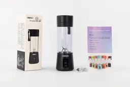 The OBERLY personal blender standing on a white table with a user’s manual, charging cable, and paper carton box by its sides.