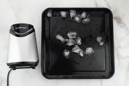 A black tray of crushed ice produced by the La Reveuse Personal Blender being on a table.