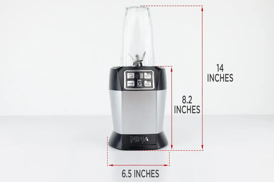 The Ninja Nutri 1000-watt personal blender standing on a gray table, with the length of its motor base being noted to the side as 8.2 inches, and the total length and width of the unit as 14 inches and 6.5 inches, respectively.