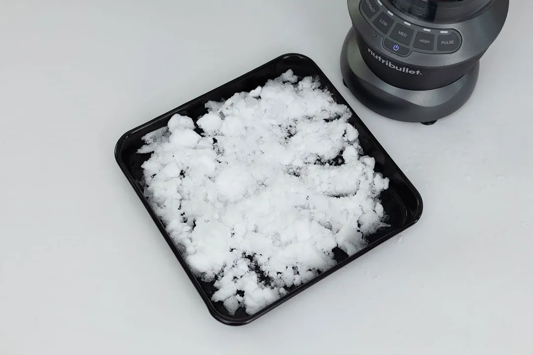 A black tray of very fine ice produced by the NutriBullet on a table.