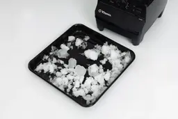 The Vitamix 5200 is beside a black tray containing its crushed ice.