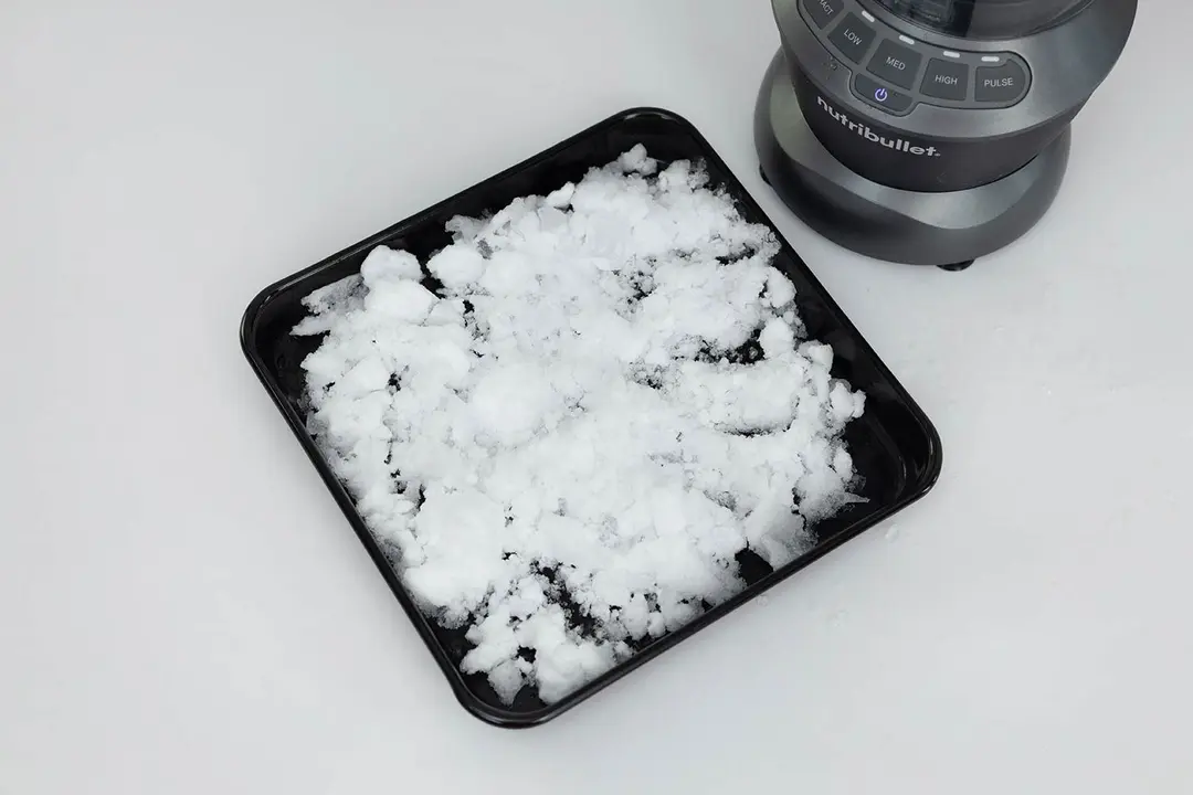 The NutriBullet ZNBF30500Z blender is beside a black tray containing its crushed ice.