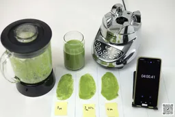 The Cuisinart SmartPower Blender motor base and its container stand on a table, accompanied by a glass filled with a green smoothie. Next to it, a white paper features three distinct smoothie samples while a smartphone showcases the blending time of 4 minutes.