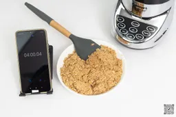 A sample of almond butter created with the Cuisinart SPB-7CH SmartPower blender is beside a smartphone and the blender’s motor.