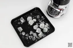 The Cuisinart SPB-7CH SmartPower blender is beside a black tray containing its crushed ice.