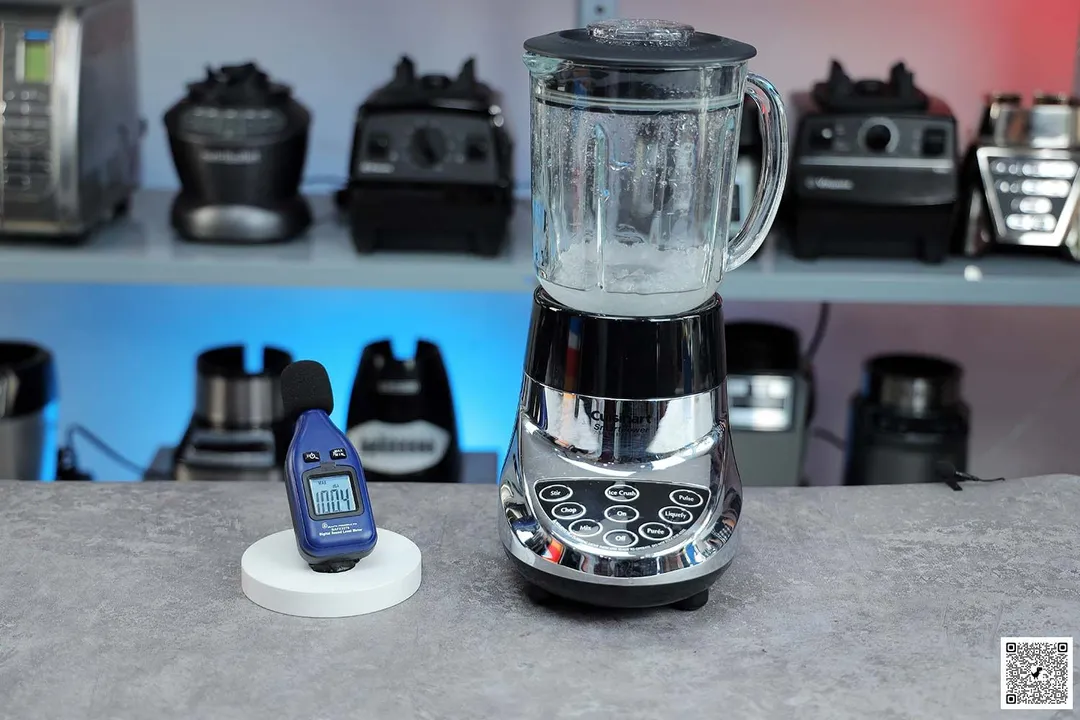 The Cuisinart SPB-7CH SmartPower blender motor base on table, hand pressing digital tachometer attached to tripod, different blenders in background.