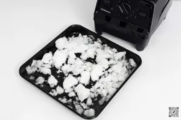 The Vitamix E310 is beside a black tray containing its crushed ice.