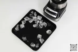 The Hamilton Beach Wave Crusher blender is beside a black tray containing its crushed ice.