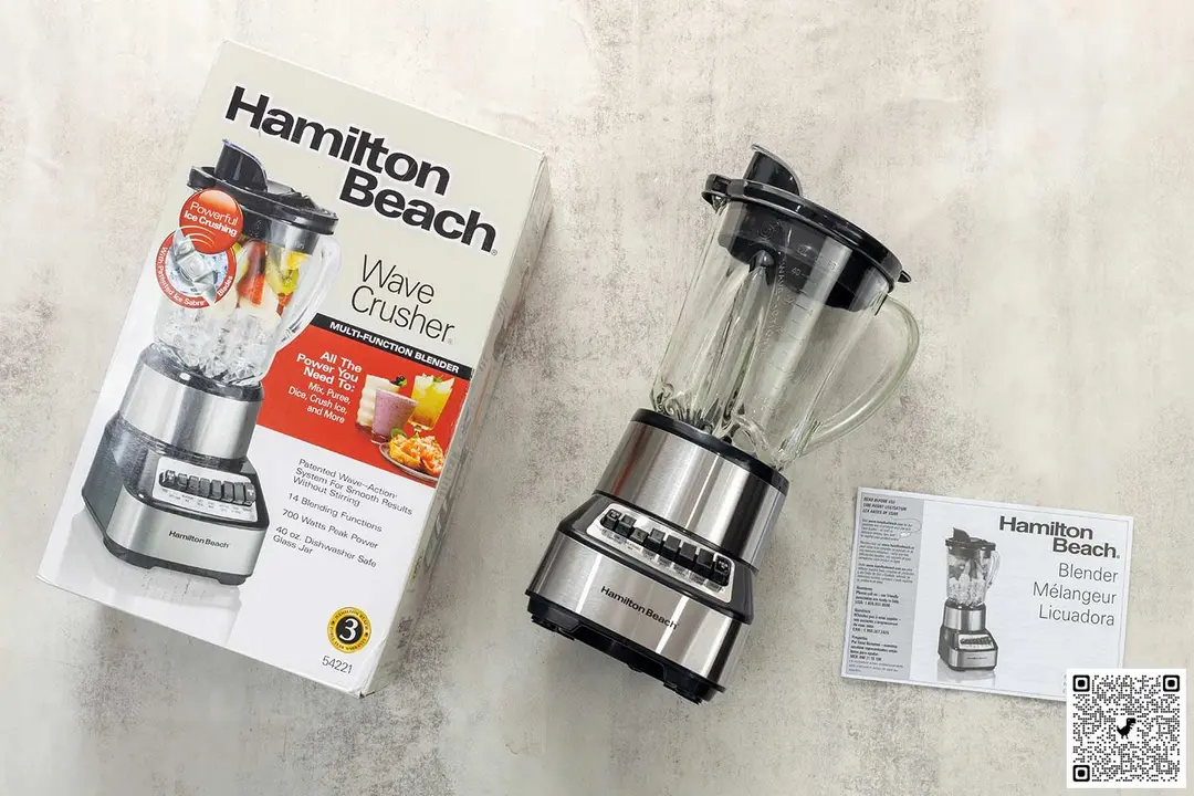 A display of the Hamilton Beach Wave Crusher blender, along with the user manual and carton box, arranged on a table.