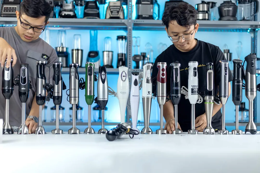 Two men arranging a row of immersion blenders on the table