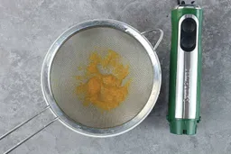 A batch of soup pureéd by the Peach Street immersion blender is checked for smoothness by being drained through a stainless steel mesh strainer.